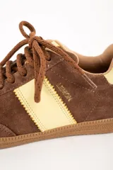 Zapatillas deportivas de gamuza color marrón con detalles en amarillo y suela de goma.