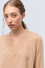 Sweater de tejido de punto color beige, con escote en V y calce holgado.