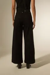 Pantalon de jean negro de corte ancho y tiro alto, con costuras verticales frontales y bolsillos laterales.