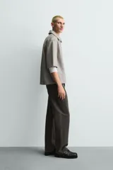 Sobrecamisa de manga corta efecto piel de corte relajado, color gris, con cuello solapa, bolsillo de parche en el pecho y cierre frontal con cremallera.