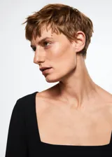 Vestido corto entallado de color negro, con escote cuadrado y mangas largas. Cuenta con cierre de cremallera en la parte posterior.