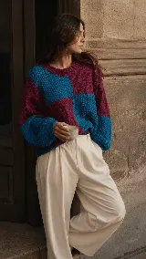 Sweater de lana merino con diseño colorblock en tonos bordó y azul turquesa, de corte relajado, con cuello redondo y texturas combinadas en punto arroz y ochos.