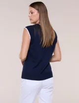 Blusa de punto fino azul marino sin mangas, con escote redondo y sisas decoradas con ribete festoneado blanco.