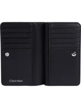 Billetera Calvin Klein plegable de piel sintética saffiano negra con estampado del logo con monograma en toda la superficie. Cuenta con diez ranuras para tarjetas, dos billeteros y un compartimento para monedas con cremallera.