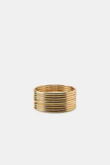 Pack de nueve pulseras rígidas metálicas doradas, de diseño fino y acabado brillante.