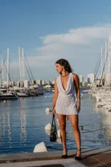 Vestido corto de encaje blanco con escote drapeado profundo, sin mangas y confeccionado en tela liviana y texturada.