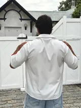 Camisa blanca de manga corta con parches de tela de colores (azul, rojo, amarillo) distribuidos irregularmente.