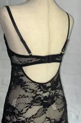 Top de encaje negro con diseño de corpiño tipo bralette y falda larga abierta al frente, con terminaciones de puntilla.