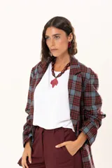 Blazer de corte oversize con estampado de cuadros en tonos azul, bordó y marrón. Presenta solapas clásicas, bolsillos con solapa en el frente y cierre frontal con botones.