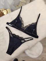 Conjunto de lencería compuesto por un corpiño triangular y una bombacha, ambos confeccionados en algodón negro con detalles de encaje en los bordes. El corpiño cuenta con breteles regulables y la bombacha presenta un diseño con tiras laterales.