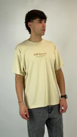 Remera de algodón color beige con estampado gráfico pequeño en el centro del pecho que incluye el texto 'Off-Court'. Presenta cuello redondo y mangas cortas con un corte holgado.