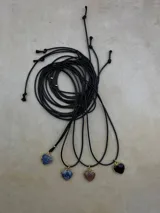 Collar de cordón negro con dije de corazón de piedra natural engarzado en borde dorado.