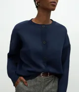 Cardigan de punto color azul marino, con corte holgado, cuello redondo, cierre frontal con botones y mangas largas con puños ajustados.