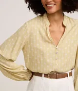 Camisa de viscosa color amarillo, con cuello padre, cierre frontal con botones y mangas largas con puños ajustados. Presenta estampa de follaje y palmeras en tono blanco.