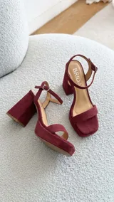 Sandalias de cuero color uva, con taco ancho, plataforma delantera y tira en el tobillo con hebilla ajustable.