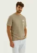 Remera de corte regular y mangas cortas, color beige, con pequeño estampado en el pecho que representa una palmera acompañada de texto.