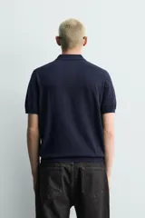 Polo de punto tejido en hilatura de algodón, color azul marino, de corte regular fit, con cuello solapa, cierre frontal de botonadura y manga corta con acabados en rib.