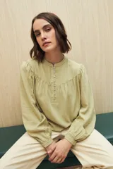 Camisa verde claro de viscosa suave, con cuello mao y botonadura parcial al frente. El detalle de frunces en los hombros y los puños abotonados le suman delicadeza y estilo.
