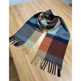 Bufanda rectangular de tejido grueso con diseño de cuadros en tonos azul, naranja, gris y beige, terminada con flecos en los extremos.