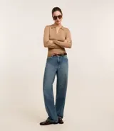 Blusa de punto ajustada color negro, con cuello polo y escote pronunciado en V. Presenta un tejido acanalado vertical en el torso y mangas largas.