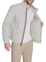 Campera tipo bomber de Tommy Hilfiger en color gris claro. Presenta cierre frontal completo, cuello mao con detalles internos distintivos de la marca, puños y ruedo elásticos, y el logo de la bandera bordado en el pecho.