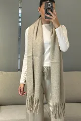 Bufanda de tejido grueso y suave, color blanco, con diseño de flecos en los extremos.