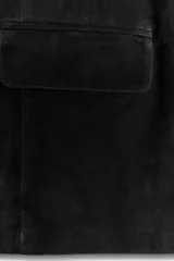 Chaqueta de ante negra con cuello solapa de muescas y manga larga. Tiene bolsillos con solapa en delantero y cierre frontal con botones.