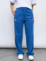 Pantalón de jogging recto en color azul, confeccionado en felpa. Presenta cintura elástica con cordón de ajuste, bolsillos laterales y detalles de la marca Umbro y el escudo del Club Nacional de Football bordados en la parte frontal.