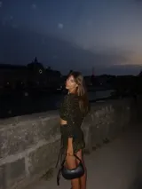 Top corto de tejido de punto negro con hilos dorados, manga larga con orificio para el pulgar, abertura en el pecho y cordones para cerrar el frente.