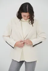 Blazer de corte clásico en color marrón, con cierre frontal de un botón, solapas con muesca y bolsillos laterales. Confeccionado en tejido estructurado.