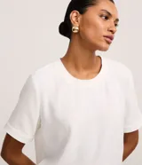 Blusa fucsia de manga corta con cuello redondo pespunteado, diseño sin estampa y efecto airflow con textura sutil. Cuenta con abertura trasera tipo gota y cierre con botón.