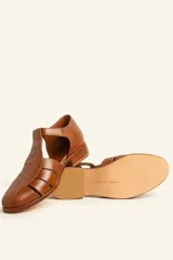 Sandalia cerrada tipo pescador de cuero negro charol, con tira en T y hebilla ajustable en el tobillo. Posee suela y taco bajo de madera.