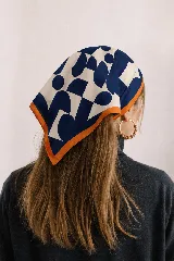 Pañuelo cuadrado de satén con estampado geométrico en tonos azul marino, blanco y celeste, con un borde naranja.