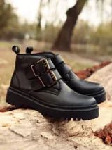 Botas cortas negras de cuero sintético con plataforma y suela track. Presentan dos correas con hebillas doradas y tirador trasero.