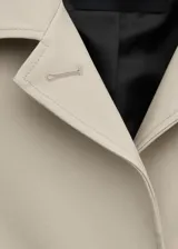 Chaqueta larga de algodón color beige, de diseño recto, manga larga, cuello camisero y cierre delantero con botones ocultos. Cuenta con dos bolsillos laterales con solapa.