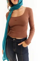 Top de manga larga color marrón, confeccionado en tejido de punto acanalado. Presenta un escote cuadrado y un detalle bordado con las iniciales BG en el centro del pecho.