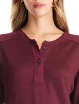 Buzo de hilado fino color bordó, con escote Henley (redondo con abertura en V y botones), hombros, puños y ruedo en tejido acanalado. Tiene una silueta cómoda y el bajo de la prenda presenta una terminación redondeada.