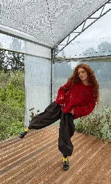 Buzo tejido a mano en lana merino, de corte oversized y diseño en bloques. Presenta un vibrante color rojo con detalles bordados a mano en forma de flores y texturas en relieve.