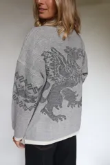 Buzo oversize de tejido de punto con diseño jacquard en mangas y espalda, cuello redondo y detalle de etiqueta de cuero sintético en el ruedo.