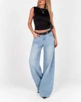 Pantalón jean de corte wide leg en tono celeste claro, de tiro medio con presillas y cierre frontal con botón y cremallera. Presenta diseño amplio en las piernas.