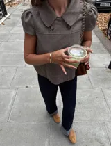 Chaqueta corta de estilo retro con estampado de mini cuadros, cuello amplio y mangas cortas abullonadas. Presenta un cierre frontal cruzado con dos botones grandes.