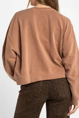 Buzo lila oversize confeccionado en 100% algodón, con cuello redondo, mangas largas y puños y dobladillo acanalados. Presenta un pequeño detalle bordado en el bajo.