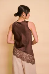 Blusa sin mangas de satén color tostado, con cuello redondo drapeado y detalle asimétrico de encaje en el ruedo.