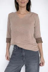 Sweater de tejido de punto color beige con escote en V y mangas largas. Presenta un detalle de estampado animal print en los puños y en el interior de la prenda, con una textura afelpada que brinda mayor abrigo.