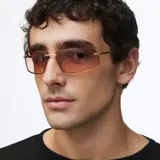 Lentes de sol rectangulares con montura de acero inoxidable color oro y lentes de nylon con degradado en tonos marrones. Presentan un diseño envolvente inspirado en los años 2000 con patillas de acetato.