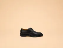 Zapato de vestir tipo oxford de cuero negro con puntera reforzada y cordones al tono.