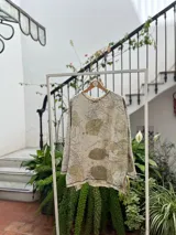 Buzo amplio de frisa liviana de algodón color gris con estampado botánico de hojas en tonos verdes. Tiene cuello redondo y tajos laterales.