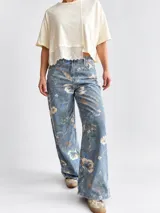 Jean wide leg de tiro alto con estampado de flores y hojas verdes, de corte amplio y cómodo.