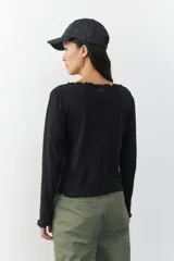 Remera blanca de manga larga con cuello redondo y costuras a la vista.