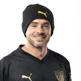 Gorro tipo beanie de la marca Puma, color negro con el logo de la marca bordado en color amarillo en la parte frontal.